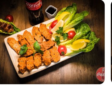 Holzbrett mit Çiğköfte-Rollen, Salatherzen, Tomaten und Zitronenspalten.
