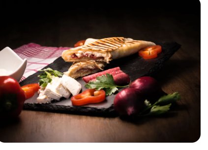 Getoasteter Wrap mit frischer Paprika, Käse und Kräutern auf dunklem Untergrund.